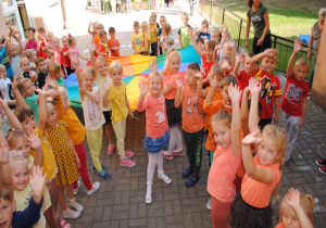 dzieci tworzą promienie słońca wg kolorów chusty i odpowiadających im kolorów ubrań